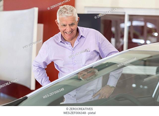 Senior man looking at a new car in showroom