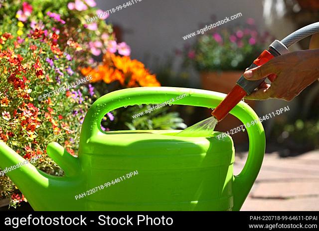 18 July 2022, Bavaria, Kaufbeuren: A woman fills a watering can with water from a garden hose in a garden. Photo: Karl-Josef Hildenbrand/dpa