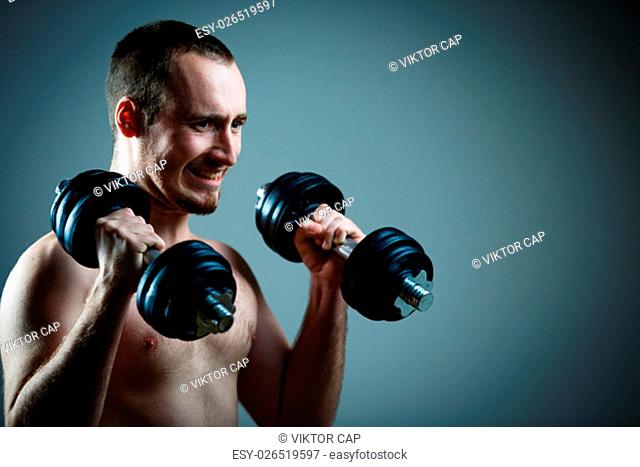 Close up of young man lifting weights over grey background (color toned image)