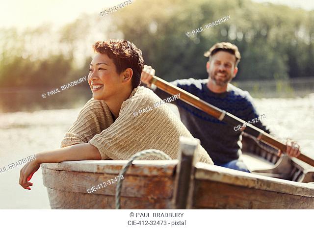Smiling couple canoeing on sunny lake