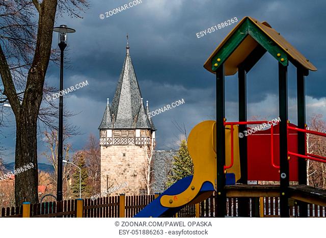 Children playground slide in the foreground of the tower of the Church of the Holliest Heart of Jesus Christ Kosciol Najswietszego Serca Pana Jezusa  in Karpacz