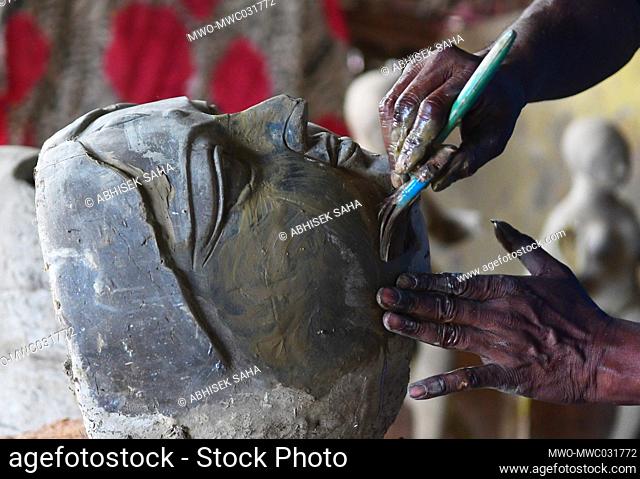 An Indian ceramic artists is sculpturing a clay face of Mother Goddess Durga at a studio, ahead of the Durga Puja festival