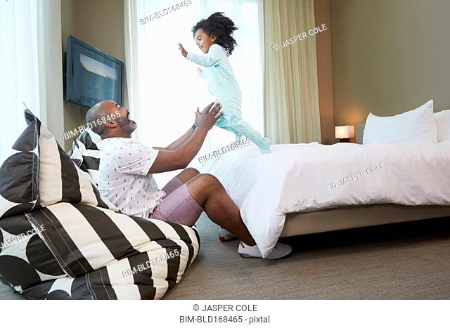 Black father and daughter playing in bedroom