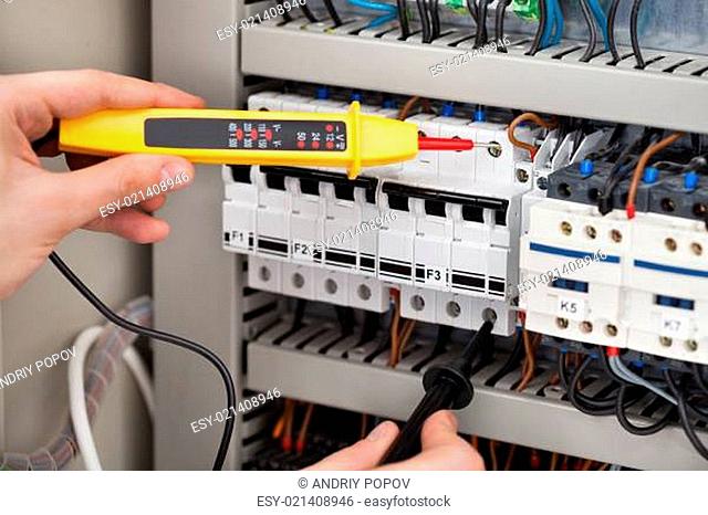 Electrician Examining Fusebox With Voltage Tester