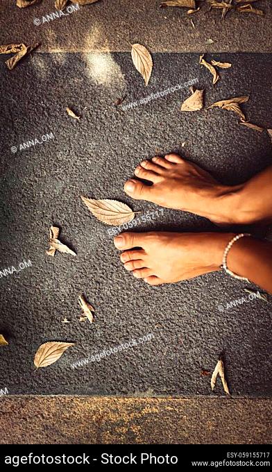 Welcome Fall Background. Closeup Concept Photo of a Barefoot Women Feet and Dry Leaves. Autumn Season Theme. Summer is Over