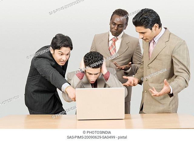 Four businessmen looking shocked in front of a laptop