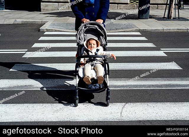 Father with baby in baby stroller crossing road in city