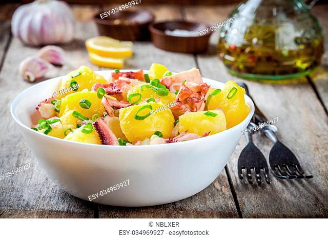 Italian food: salad with octopus, potatoes and onions on rustic background