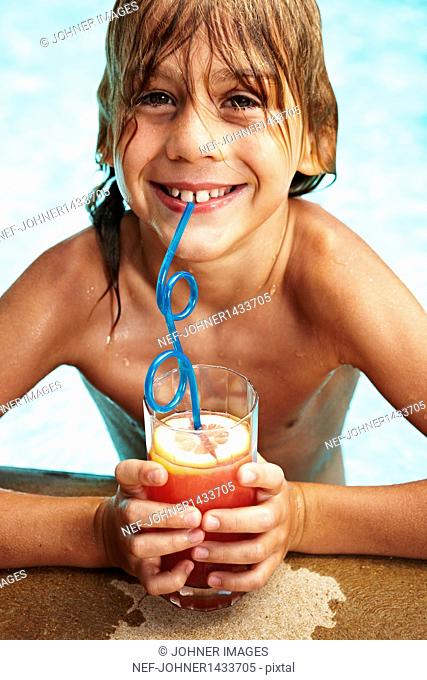 Portrait of boy in swimming pool drinking juice