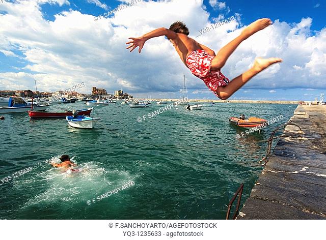 Children jumping in water at Muelle Don Luis. Castro Urdiales Bay, Cantabria, Spain