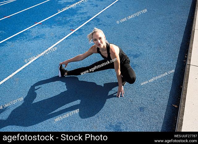 Sportswoman doing warm up exercise on track