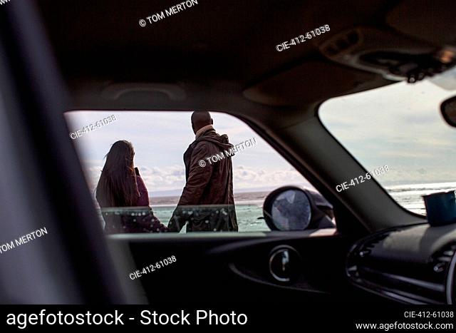 Couple holding hands outside car on winter beach