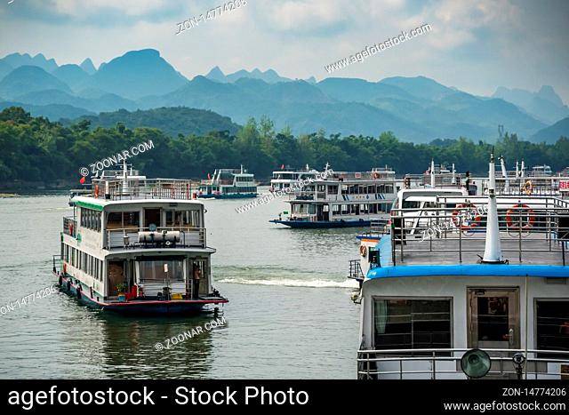 Guilin, China - August 2019 : Sightseeing boats full of tourists departing on a trip on the magnificent Li river from Guilin to Yangshuo
