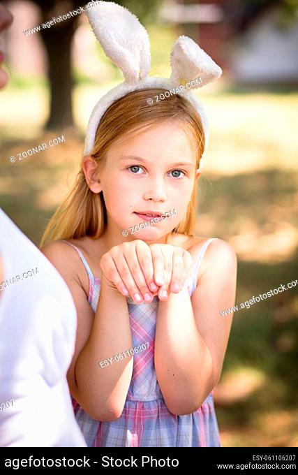 Little girl with bunny ears posing for photo. Pretty little girl wearing bunny ears, holding hands together