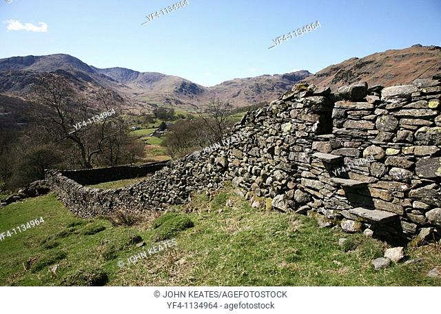 A stile in a dry stone wall looking towards Great Langdale Fells near to Elterwater in the Lake District National Park, Cumbria, England