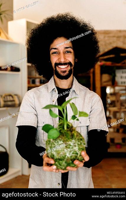 Cheerful man holding kokedama plant at home