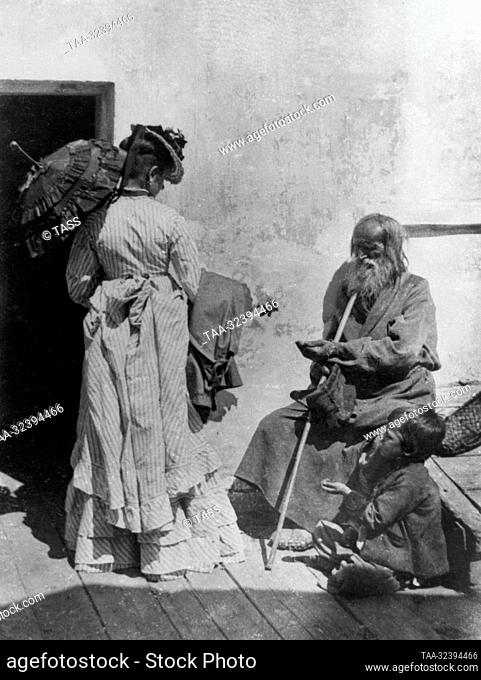 Around 1900. Nizhny Novgorod, Russian Empire. A woman gives alms to beggars. The picture was taken by Russian photographer Andrey Karelin