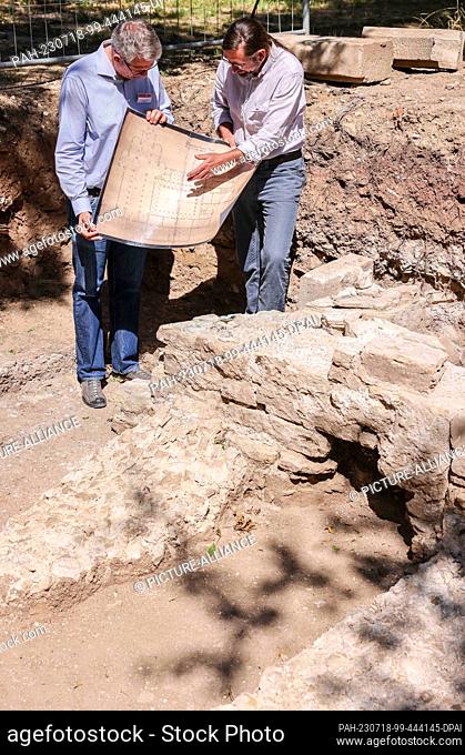 18 July 2023, Saxony-Anhalt, Zeitz: Holger Rode (r), excavation manager, and Donat Wehner, project manager, stand with a historical plan during excavation work...
