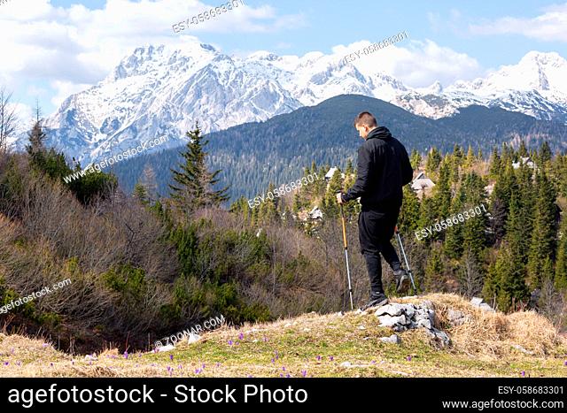 Casual and active healthy man hiking in Alpine mountains with trekking poles