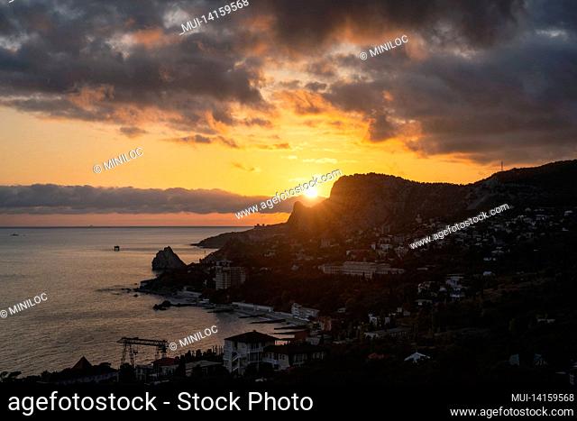 sunet over simeiz village with silhouette of cat mountain and diva rock duroing golden hour. southern coast of crimea