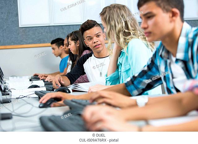 Row of high school students concentrating in computer class