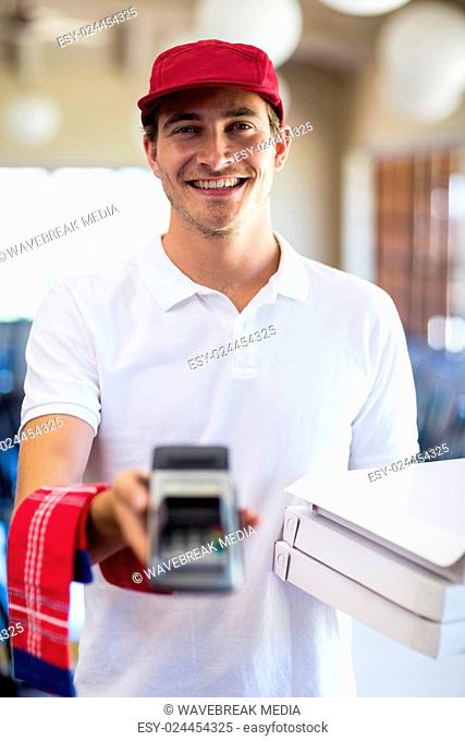 Happy pizza delivery man showing credit card machine
