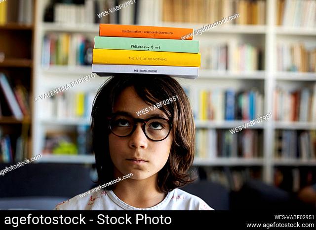Portrait of boy balancing stack of books on his head