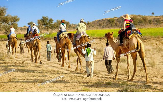 Camel caravan safari ride with tourists in Thar Desert near Jaisalmer, India
