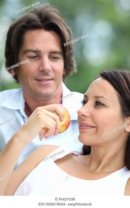 Couple relaxing in the park and eating an apple