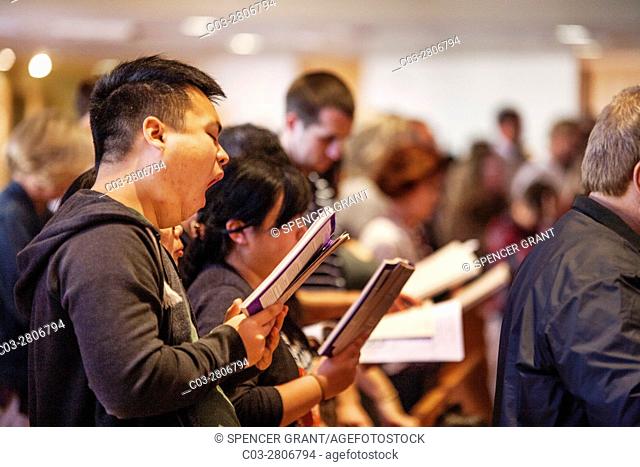 An Asian American parishioner yawns while singing a hymn during mass at a Laguna Niguel, CA, Catholic church