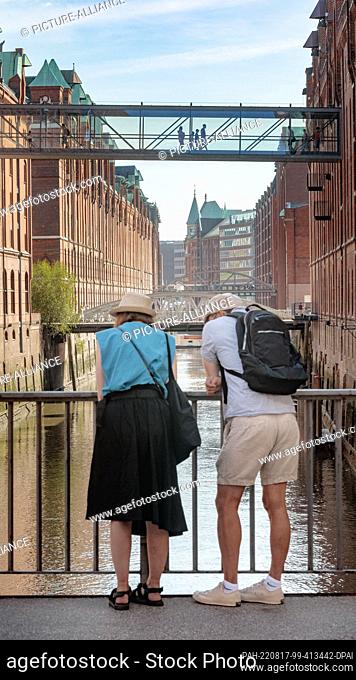 15 August 2022, Hamburg: A couple stands on the sand bridge in the Speicherstadt Hamburg and looks over the Kehrwiederfleet