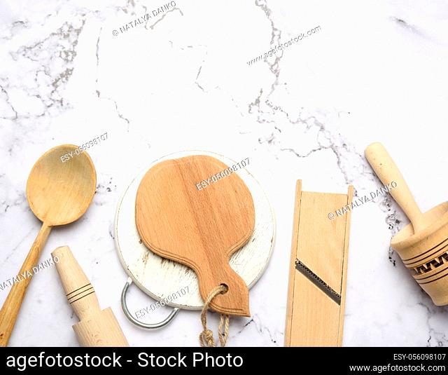wooden kitchen utensils on white marble table, top view, copy space