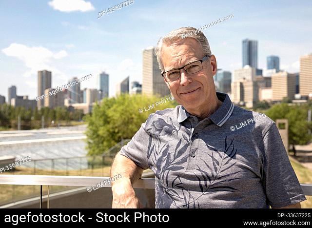 Outdoor portrait of senior man with eyeglasses, city skyline in the background; Edmonton, Alberta, Canada