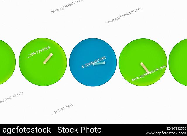 Close up detailed top view of green candles in a row with a blue one in the middle, isolated on white bakground
