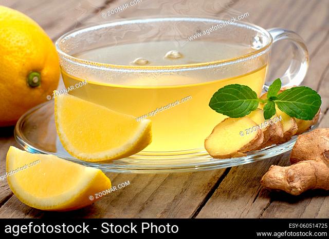 Heißer Tee mit Zitrone und Ingwer auf rustikalem Holz