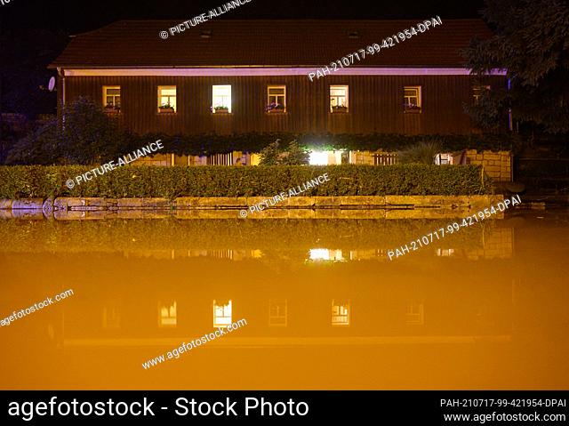 17 July 2021, Saxony, Bad Schandau: A street is slightly flooded with water from the Kirnitzsch in front of a residential building