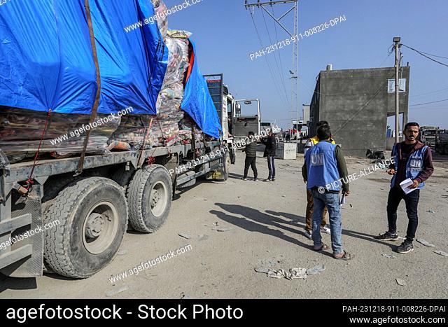 18 December 2023, Palestinian Territories, Rafah: UN workers look on as aid trucks enter Gaza through the Kerem Shalom commercial crossing