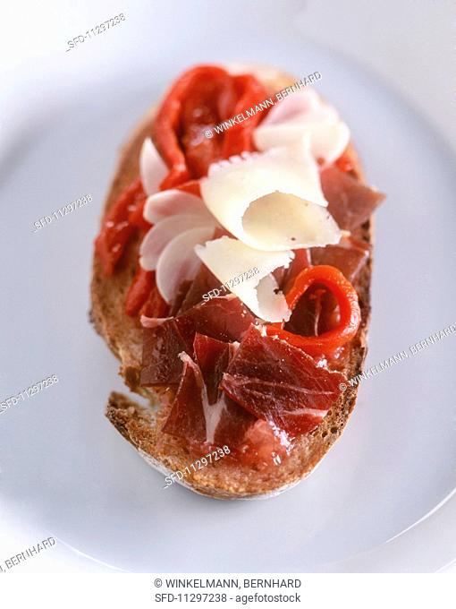 A slice of toasted bread topped with pata negra and manchego cheese