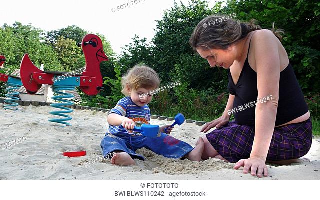 pregnant Mother with her little boy in a sandpit, Germany