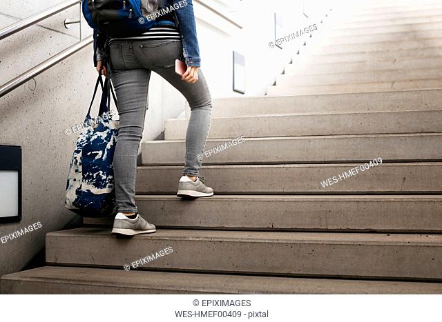 Woman with bag and backpack walking up stairs at the station