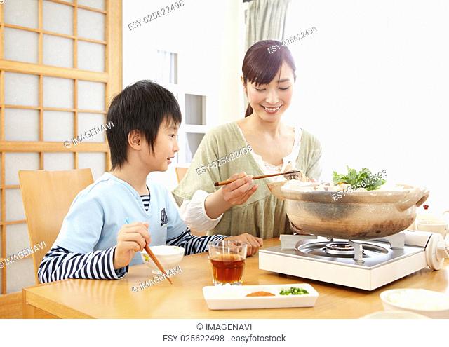 Mother and son sitting around Japanese hot pot