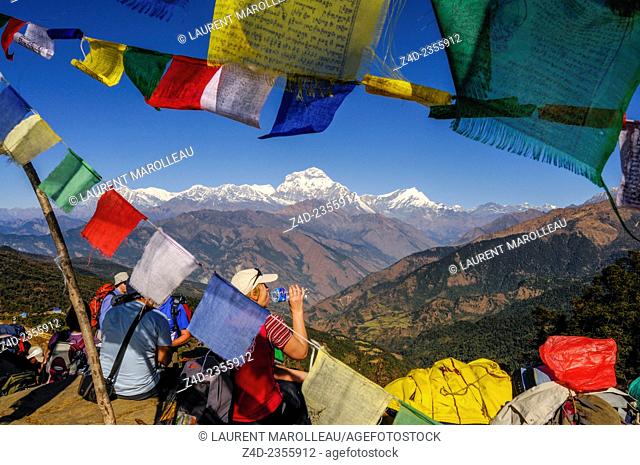Buddhist Prayer Flags and Trekkers Stops for a break with Dhaulagiri Range in Background, between Ghorepani and Tadapani Village