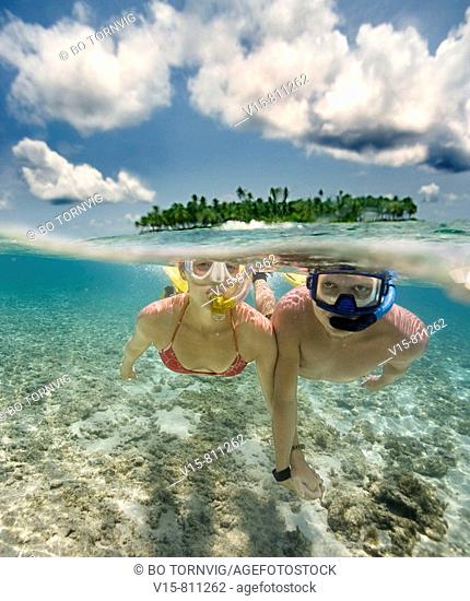 couple swimming in front of remote tropical island