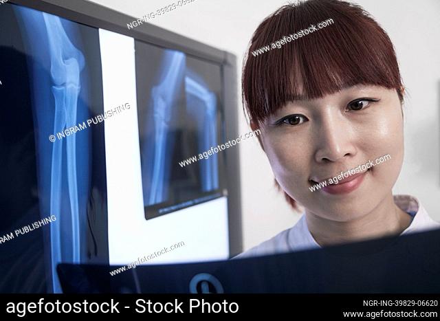 Smiling female doctor looking at x-ray of human bones