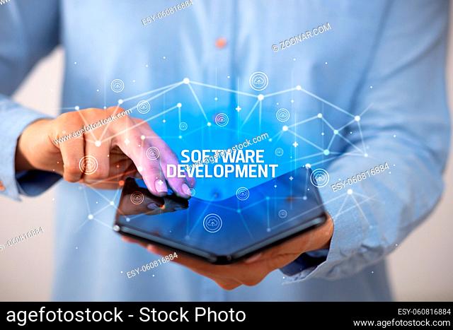 Businessman holding a foldable smartphone with SOFTWARE DEVELOPMENT inscription, new technology concept