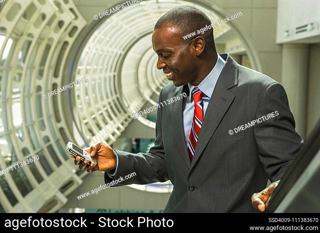 Black businessman text messaging on cell phone