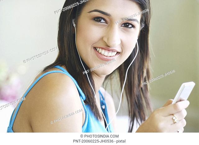 Portrait of a young woman wearing headphones listening to an MP3 player