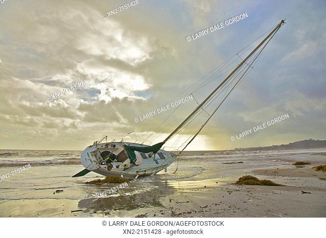 As the storm that ran it aground clears, a sailboat lies high and dry on East Beach, Santa Barbara, California, United States