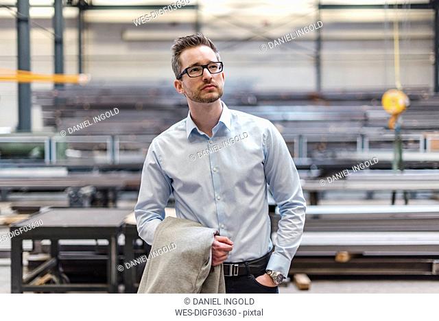 Portrait of businessman on factory shop floor thinking