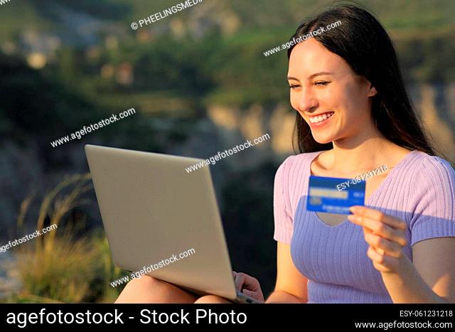 Asian woman buying online with credit card and laptop in the mountain